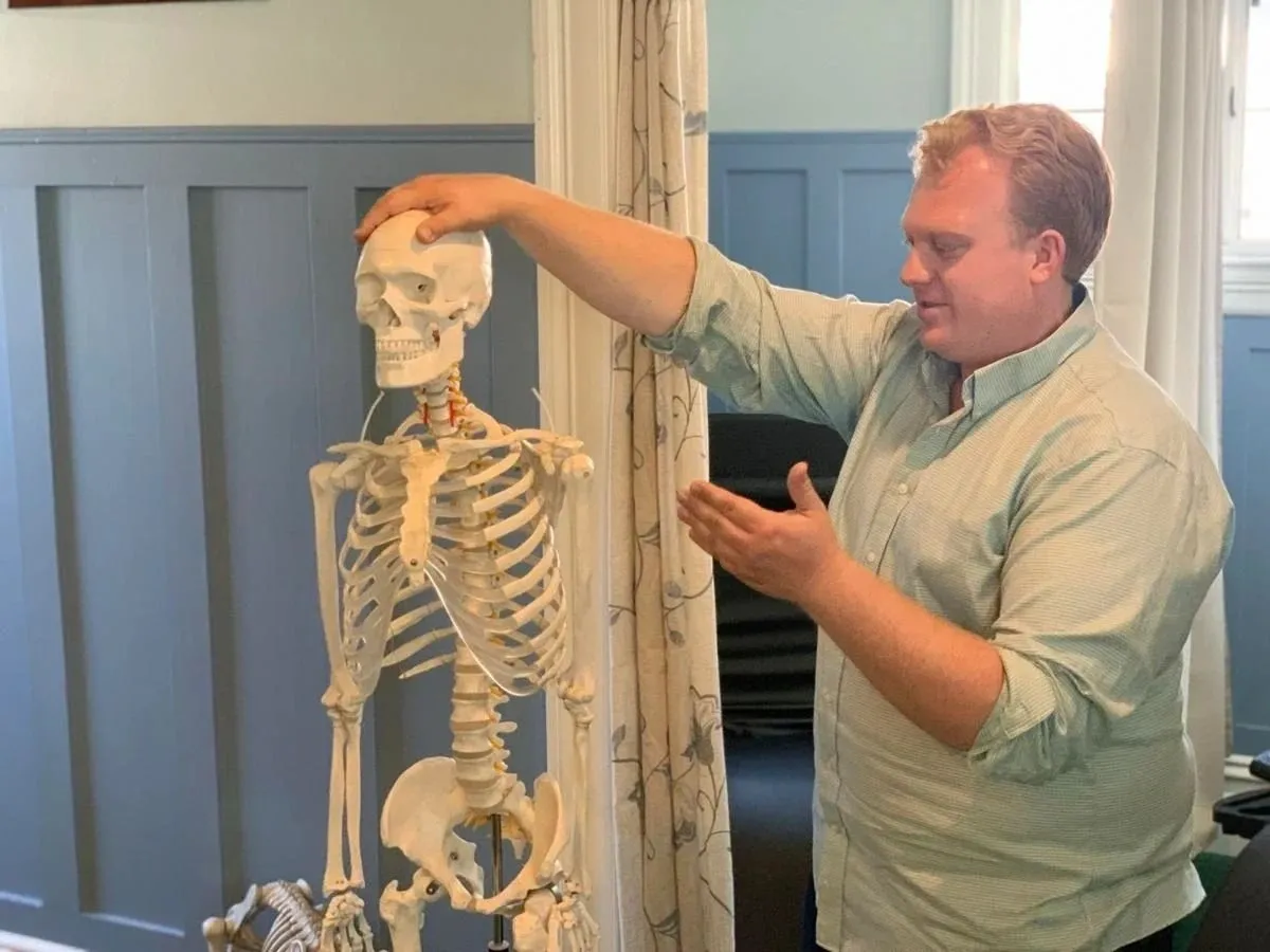 A man standing next to a skeleton.